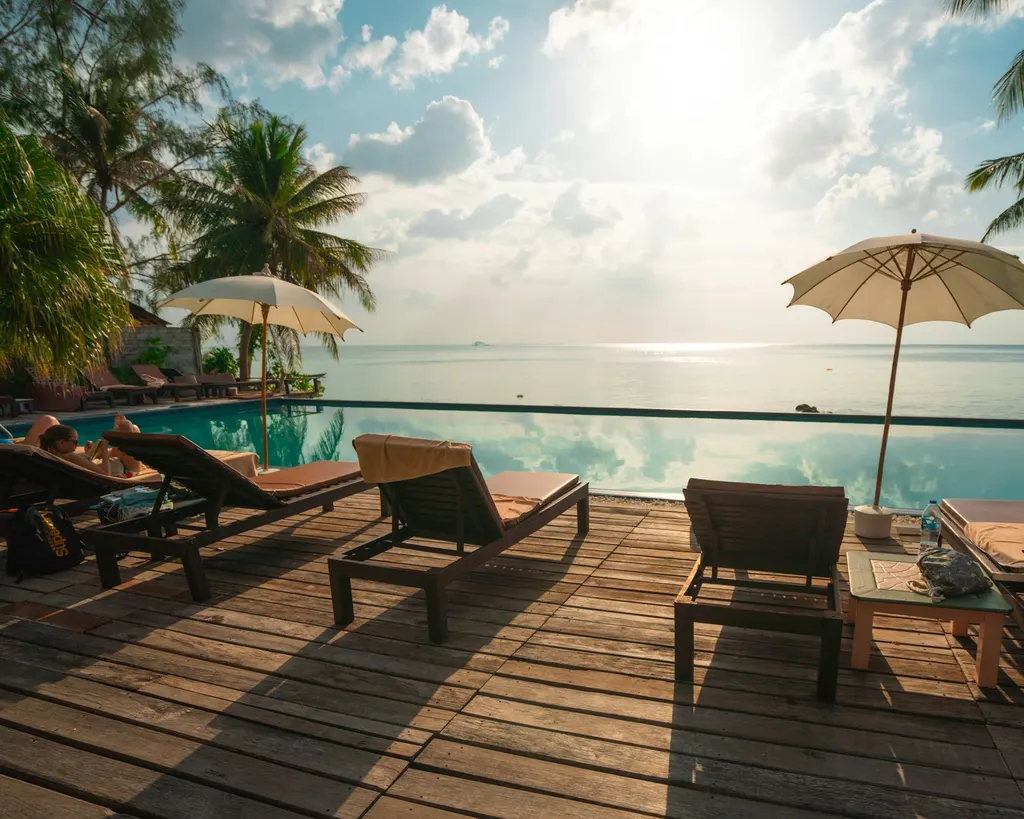 A resort main pool lined with loungers at sunset